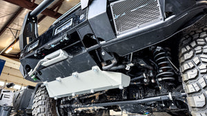 Low-angle shot of the INEOS Grenadier front protection system, showcasing the reinforced lower crossbar, mega-duty skid plate, and high-clearance design for off-road suspension