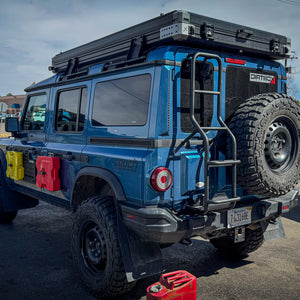Fully equipped blue Ineos Grenadier featuring the rear ladder with integrated jerry can holder for increased fuel range during off-roading
